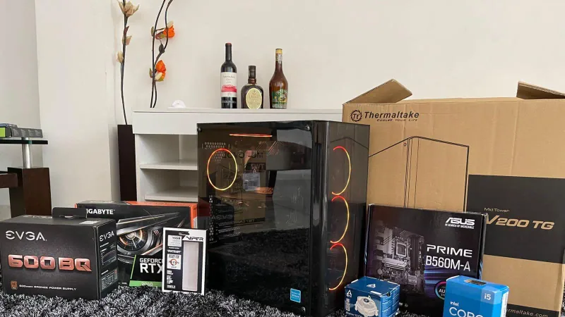 Componentes de un PC gamer alineados antes del ensamble: fuente EVGA, tarjeta gráfica RTX 2060, gabinete Thermaltake, board ASUS y procesador Intel Core i5